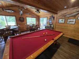 a red felted pool table set up and ready to be used in a fishing lodge